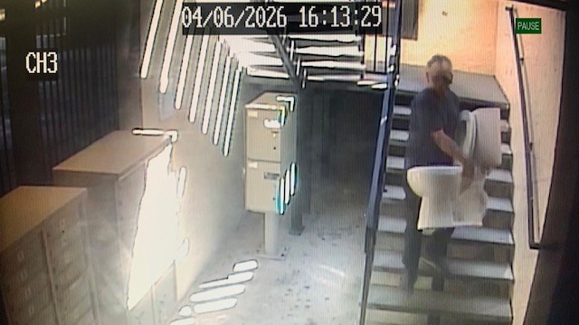 man carrying old toilet down stairs